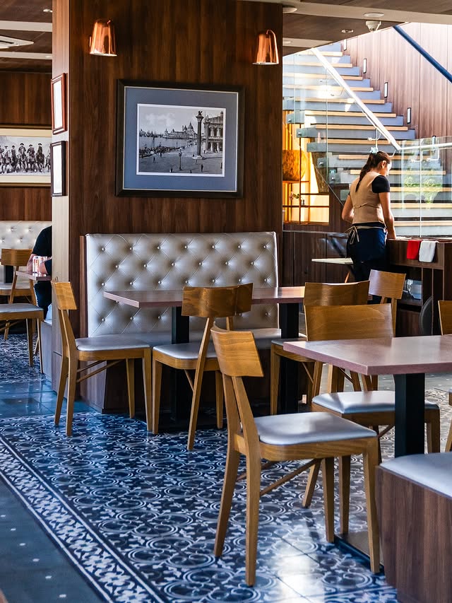 Comedor de Raconto Los Andes con cuadros, madera y escalera