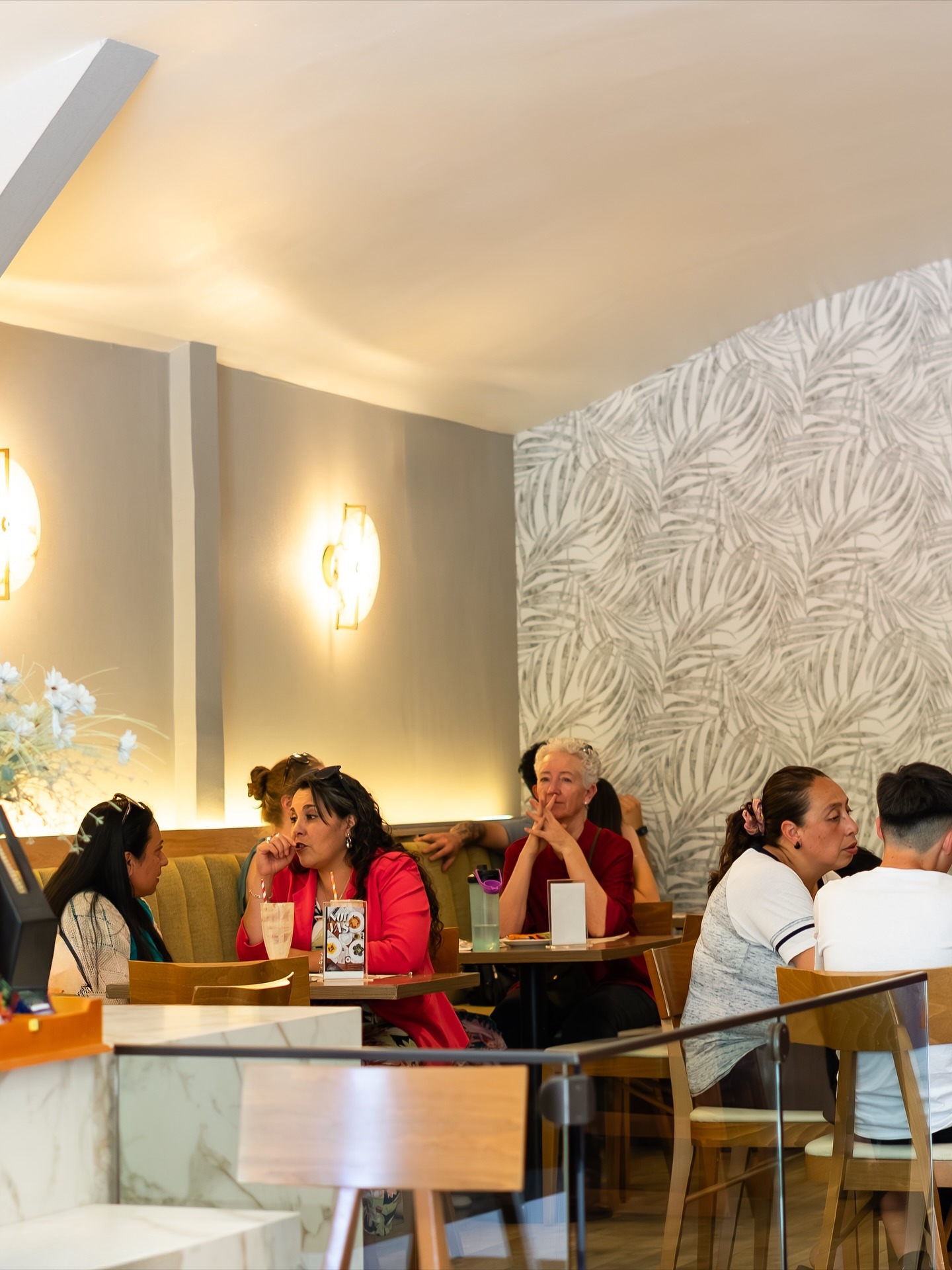 Salón claro de Raconto San Felipe con murales de palmeras y luz cálida